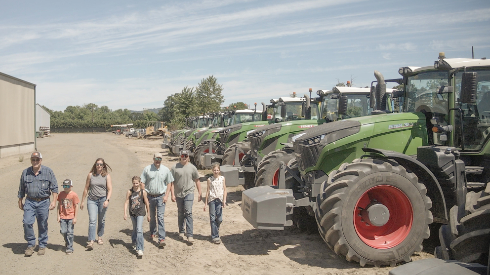 Family of seven walks by their fleet of Fendt tractors